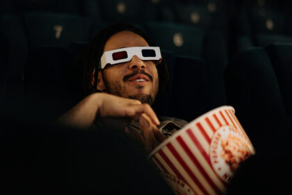 Homem no cinema com óculos 3D e um balde de pipocas a ver supostas mensagens subliminares colocadas secretamente num filme