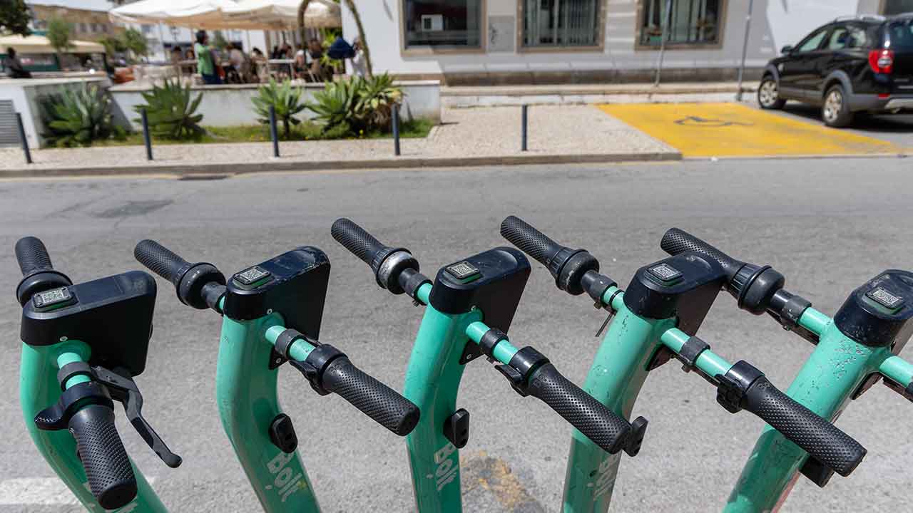 Trotinetes elétricas a circular em contexto urbano com trânsito misto.