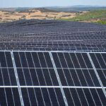 Painéis solares instalados numa vasta área de terreno rural.